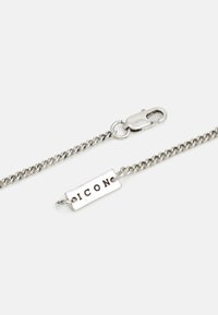 Silver chain bracelet featuring a rectangular plate with "ICON" engraved. Includes a lobster clasp for closure. Textured metal finish.