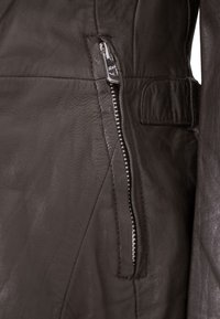 Schwarze Lederjacke mit einem Reißverschlusstasche, glatter Textur und schlankem Design mit dezentem Glanz. Akzentuiert mit minimalistischen Hardware-Details.