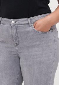 Slim fit, szürke farmernadrág, denim anyagból készült. Gombos záródással, elülső zsebekkel és látható varrással a varrások mentén.