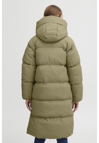 Lang, fluffy jakke i dæmpet olivengrøn med hætte. Har vandrette quiltede sektioner og en længde til midt på læggen. Glat, mat tekstur.