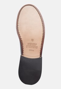 Leather shoe sole with a tan upper, black rubber bottom, and embossed text "HENRY STEVENS BERLIN." Stitched edge detailing visible.