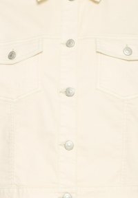 Devant de veste couleur crème avec boutons-pression argentés et deux poches poitrine à rabat avec fermeture par bouton.