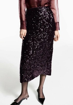 Vrouw draagt een donkerpaarse pailletten kokerrok met een asymmetrische zoom, een doorzichtige bordeaux blouse, zwarte transparante panty en zwarte slingback hakken.