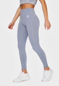 Lekkie szare legginsy z wysokim stanem, uszyte z elastycznego materiału, z bocznym szwem podkreślonym kropkowanym detalem i logo.