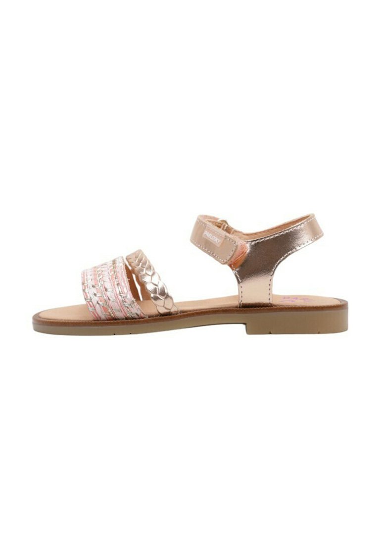Sandalias metálicas doradas con dos correas anchas, una de ellas con un detalle trenzado en rosa y plateado. Suela plana, correa ajustable en el tobillo y textura suave.