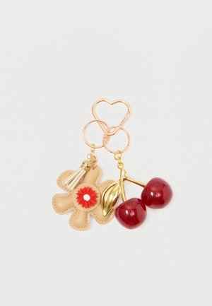 Gold heart-shaped hoop earrings feature a tan leather flower with a red center and a pair of shiny red cherry charms.