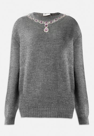 Pilkas megztinis su raukšlėtą struktūrą, apvaliu kaklu ir papuošimu su brangakmeniais ant apykaklės, kurio sudėtyje yra violetinių ir skaidrių akmenų.