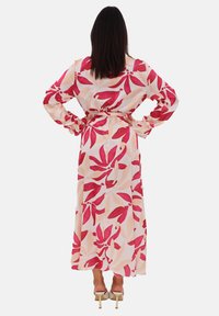 Robe maxi en tissu léger avec un motif floral rose et rouge. Dotée de manches longues, d'une taille cintrée et d'une silhouette fluide.