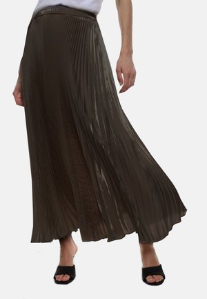 Gonna maxi plissettata di color marrone scuro, realizzata in tessuto leggero e lucido. Presenta una vita elastica e una consistenza morbida. Sandali neri open-toe.