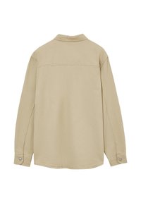 Chemise à manches longues beige clair avec col, poignets à boutons et texture lisse, dotée d'un ourlet droit et d'un détail de couture au niveau du dos.