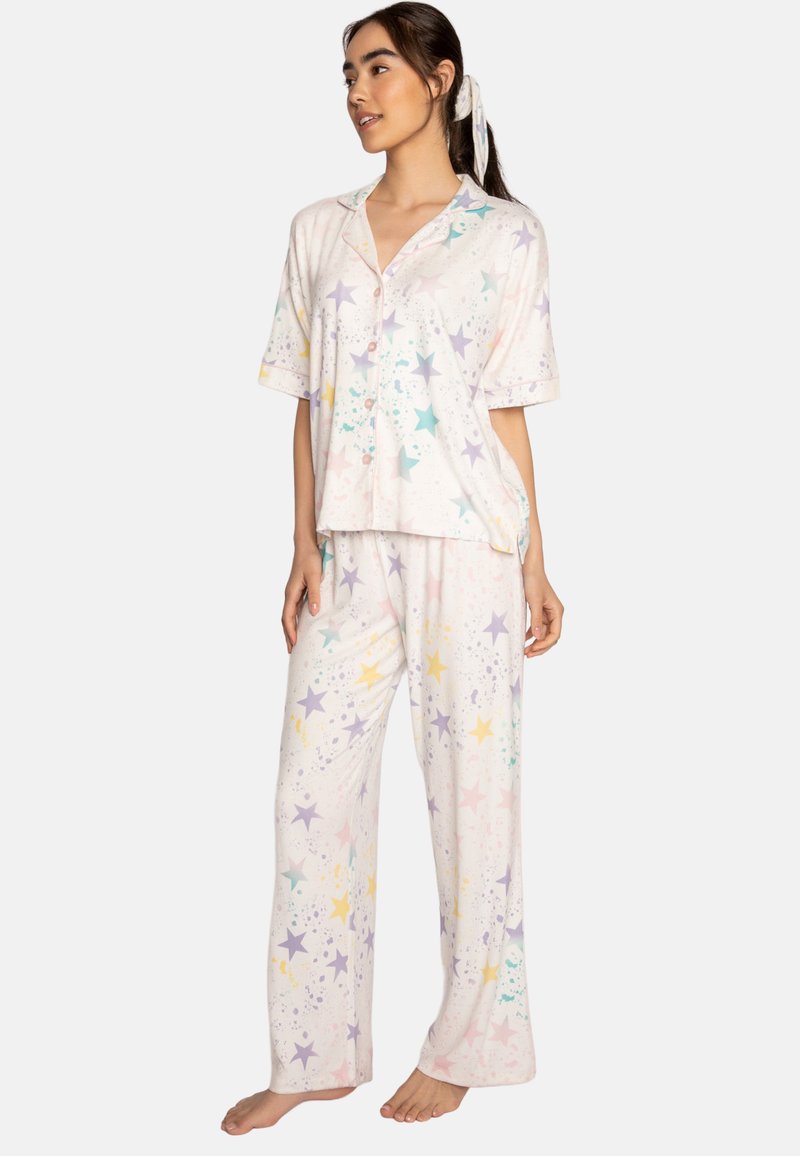 Short-sleeve, button-up pajama set in soft fabric featuring pastel stars and splatter patterns on a light background; loose-fitting trousers.