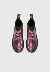 Botas de tobillo metálicas moradas con un patrón texturizado de piel de serpiente, acentos negros y cordones rosas. Cuentan con una cremallera lateral y una lengüeta amarilla.