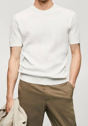 Suéter blanco de punto acanalado de manga corta con escote redondo y dobladillo ajustado, combinado con pantalones caqui. Textura suave, diseño limpio.