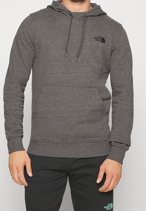 Man wearing a charcoal gray The North Face hoodie with front kangaroo pocket and matching dark pants with logo on left thigh.