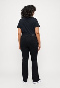Sorte videbukser med sprett laget av denim, med høy midje, to baklommer og et glatt frontdesign, kombinert med en svart t-skjorte med korte ermer.