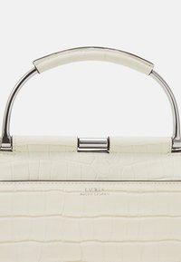 Vitt krokodilmönstrat läderhandtag med en handtag i silverfärgad metall och en märkesplakett. Slät textur med en strukturerad form.