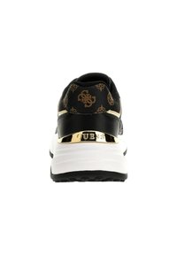 Sneaker nera con accenti dorati, caratterizzata da una parte superiore testurizzata, motivi del logo, suola bianca imbottita e un dettagli spigoloso dorato sul tallone.