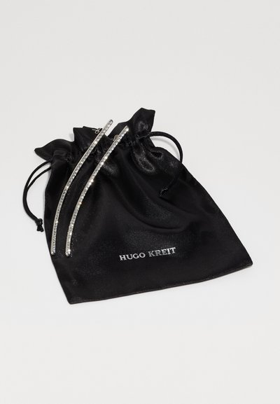 Pungă neagră din satin cu șnur, având logo-ul "HUGO KREIT". Include două bare decorative argintii cu embellishementuri clare deasupra.