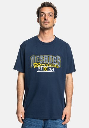 Navy blue cotton T-shirt featuring large white and yellow "DC Shoes Worldwide" graphic, short sleeves, and a crew neckline.