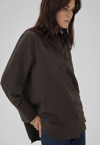 Braun gestreiftes Button-Up-Hemd mit lockerer Passform, das über einen Kragen und lange Ärmel verfügt. Weicher Stoff mit einer glatten Textur.