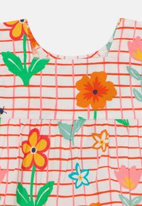 Vestido de patrón floral con escote redondeado; presenta flores naranjas, rosas y verdes sobre un fondo de cuadrícula blanca. Tejido de algodón suave.