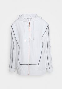 Vit sportjacka med dragkedja fram, huva, elastiska ärmslut och nederkant. Har grå detaljer och roséguldsmaterial, logotyp på bröstet och en etikett.