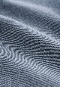 Nahaufnahme von blau-weiß gestreiftem Stoff mit weichen Falten und sichtbarer feiner Textur.