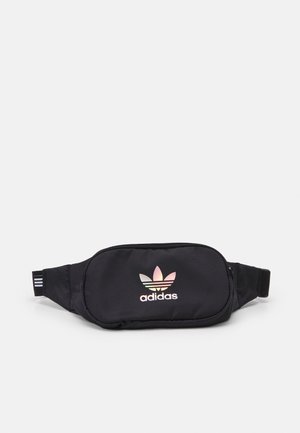 Sac banane en tissu noir avec fermeture éclair, doté d'un logo Adidas réfléchissant et d'une sangle réglable rayée pour un port sécurisé.