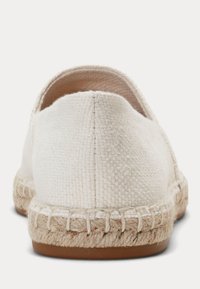 Bela tkanina espadrila, gledana od zadaj, z podplatom iz juta vrvi z vidnim šivom in ravnim gumijastim podplatom.