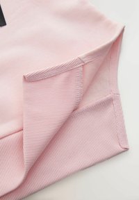 Tessuto di felpa rosa con una superficie liscia e orlo a coste. Presenta cuciture pulite e un dettaglio con bordo ripiegato.