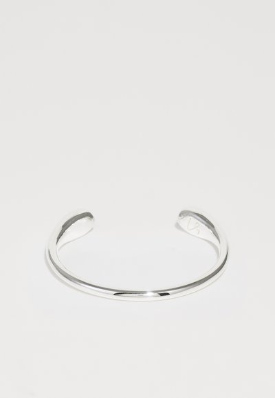 Hõbedane käevõru, mille pind on sile ja poleeritud. Omab avatud otste kergeid curves. Minimalistlik disain, ilma täiendavate kaunistusteta.