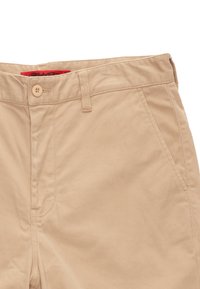 Beige katoenen chino-broek met een enkele knoopsluiting, riemlussen en schuin geplaatste zijzakken. De stof heeft een gladde textuur en minimale stiksels.