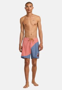 Herren Badehosen in pinken und blauen Farbblöcken, aus leichtem Material, mit verstellbarem Bund und seitlichem Logo-Patch.