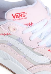 Buty do skateboardingu Vans z różowym zamszowym i siateczkowym cholewką, białymi sznurowadłami oraz czerwonymi detalami szwów; zaokrąglony nosek i teksturowana gumowa podeszwa.