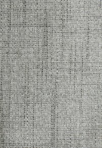 Gros plan sur un tissu gris tissé avec un motif en grille texturé de petits carrés serrés.