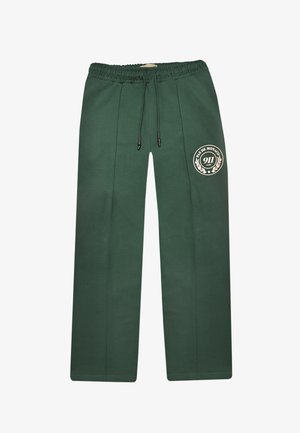 Pantaloni della tuta verde scuro con cintura elastica, dettagli con cuciture frontali, coulisse e logo "Pas de Monaco 911 Club" sulla coscia sinistra.