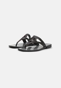 Svarta platta sandalskor med en stilren design, som har en tånopp och utskurna mönster på de övre remmarna. Slät, blank fotbädd.