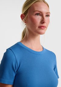 Niebieska koszulka z prążkowanej tkaniny, z okrągłym dekoltem i krótkimi rękawami, wykonana z elastycznego materiału, charakteryzująca się gładką fakturą i dopasowanym krojem.