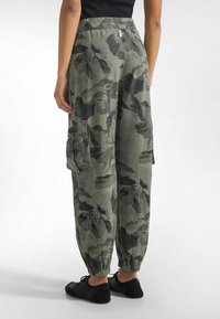 Pantalones cargo en verde oliva con un patrón floral. Presentan cintura elástica, bolsillos laterales y puños ajustados para un ajuste relajado.