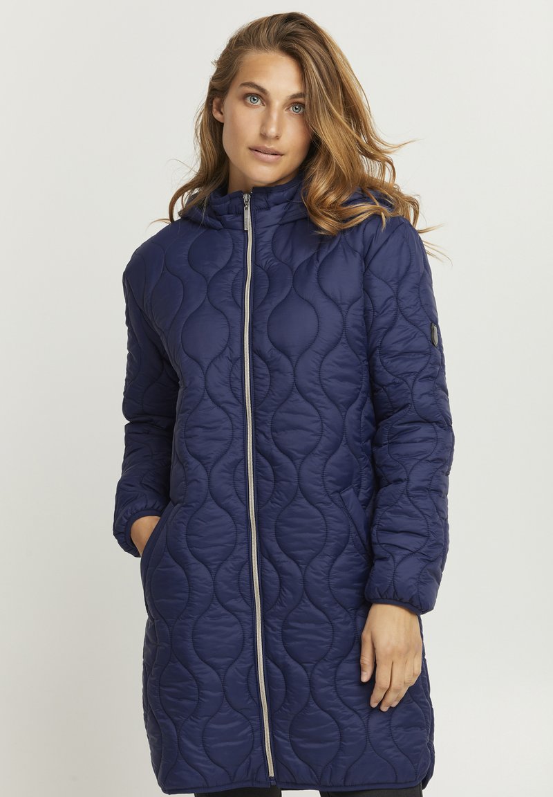 Cappotto lungo imbottito blu navy con chiusura a zip, cappuccio e tasche laterali. Presenta un motivo a onda testurizzato e polsini elasticizzati.