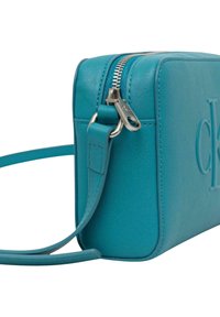 Sac à main en cuir bleu sarcelle de forme rectangulaire, avec fermeture éclair et détail de logo embossé. Comprend une bandoulière amovible.