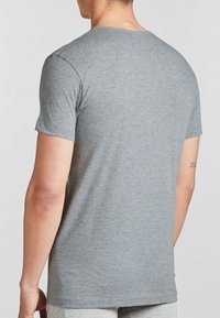 T-shirt grigia a maniche corte, realizzata in tessuto morbido, con scollo rotondo. La parte posteriore è semplice con una vestibilità comoda. Nessun motivo o dettaglio visibile.