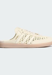 Μπεζ sneaker χωρίς κορδόνια με πλεκτές πλευρές, δερμάτινη μύτη, κορδόνια μπροστά, σόλα από καουτσούκ και τη λέξη «Samba» γραμμένη με χρυσά γράμματα στο πλαϊνό πάνελ.