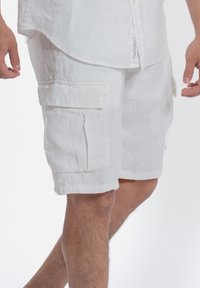 Witte linnen cargoshorts met zijzakken en een relaxte pasvorm. De stof heeft een soepele textuur en valt natuurlijk.