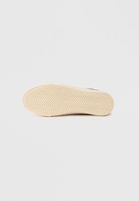 Μπεζ λαστιχένια εξωτερική σόλα με σχέδιο ψαροκόκαλο, ελαφρώς υφασμένη. Ομαλή επιφάνεια με στρογγυλεμένο σχήμα, σχεδιασμένη για υποδήματα.