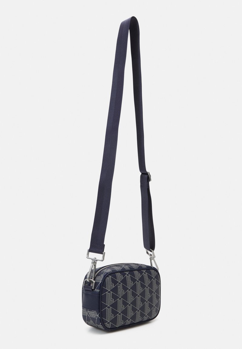 Sac bandoulière bleu marine avec un tissu à motif géométrique, de forme rectangulaire, bandoulière réglable et accents en métal argenté.