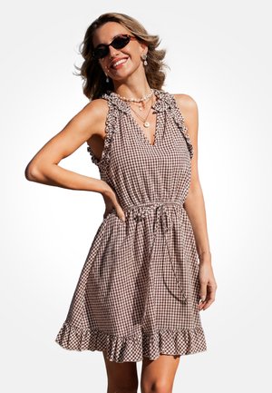 Vestido de cuadros vichy marrón y blanco, tirantes con volantes, escote en pico, cintura elástica, falda acampanada con bajo con volantes. Sin herrajes ni adornos visibles.