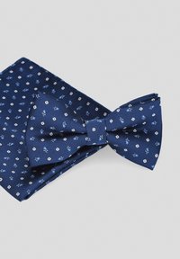 Granatowy zestaw muszki i poszetki z jedwabiu z białymi wzorami kwiatowymi. Muszka ma centralny węzeł i kształt motyla.