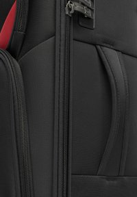 Černý texturovaný tkaninový batoh se zipy, boční kapsou a kontrastní barvou vnitřku. Obsahuje pevné kovové prvky a zesílené švy.