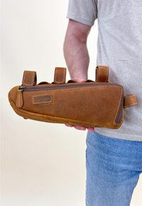 Brown leather travel pouch with a zipper, featuring two looped straps, slightly rounded shape, and visible stitching detail.